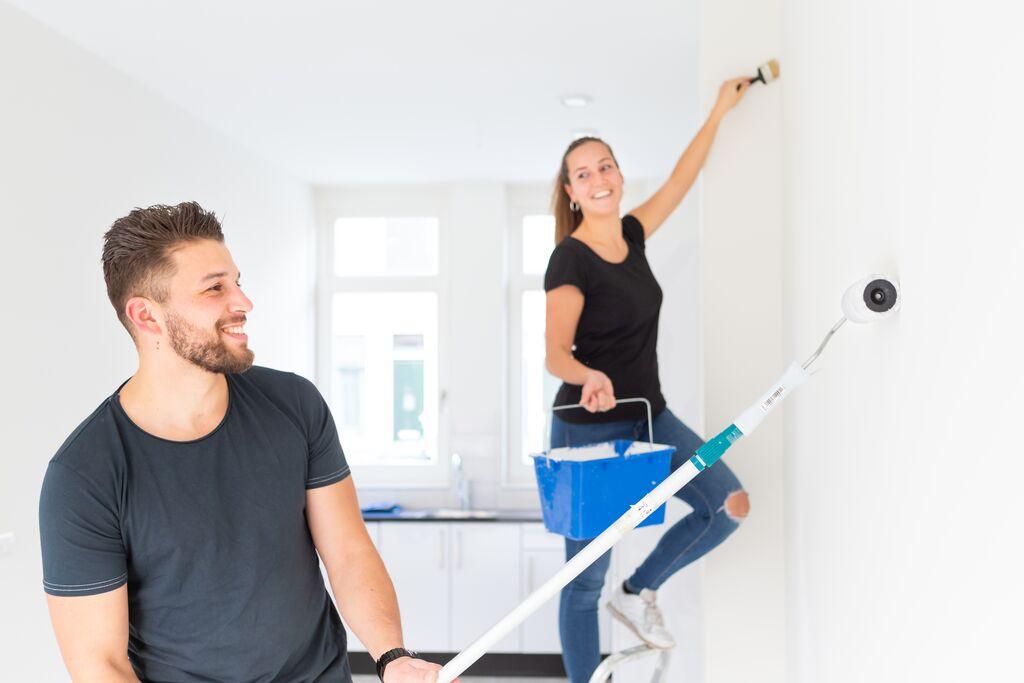 Twee studenten zijn de muren van een woning aan het verven.