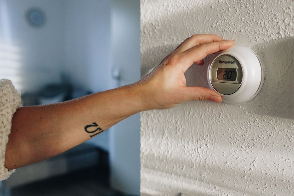 Iemand verandert de temperatuur via een thermostaat