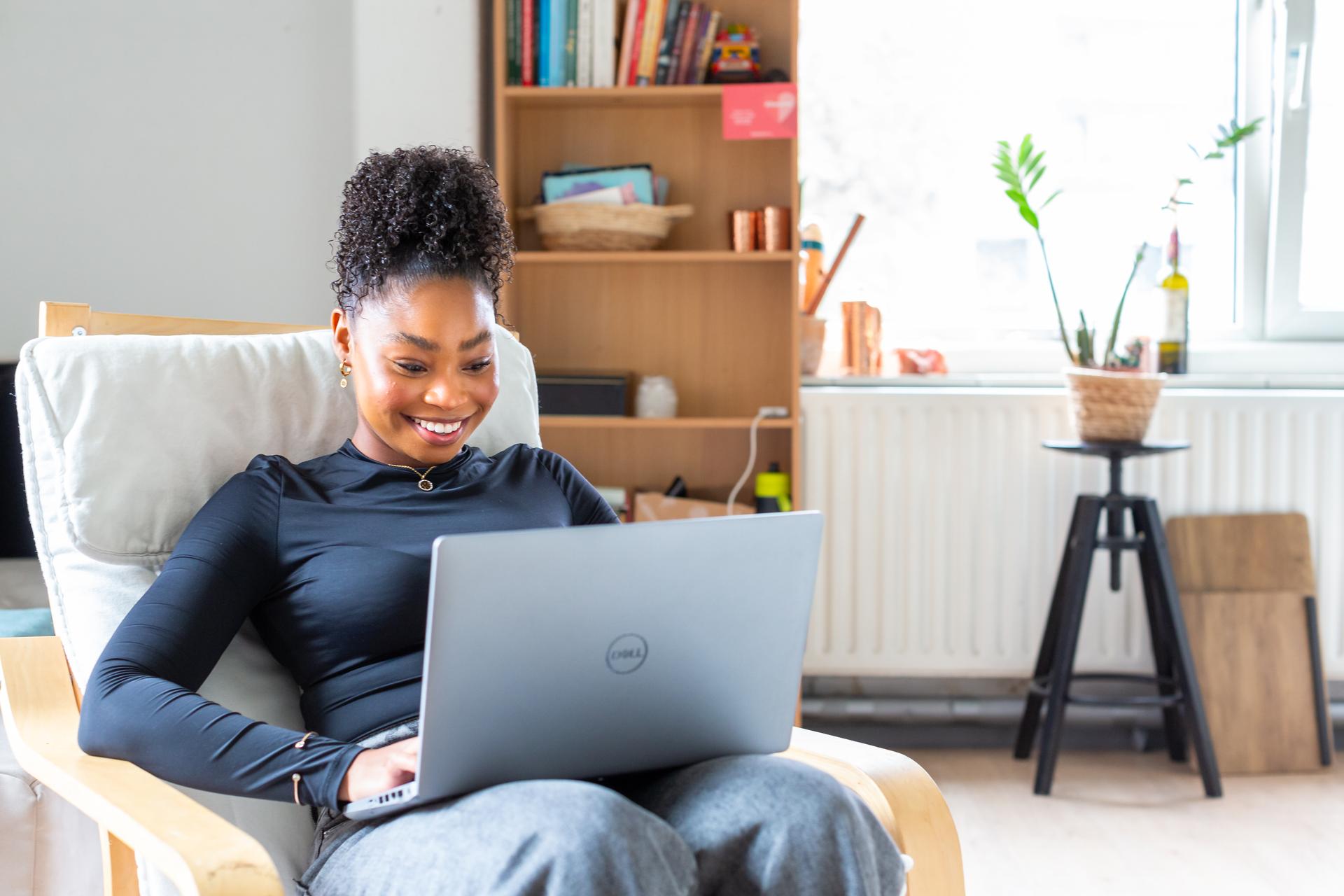 Lachende vrouw met laptop op schoot