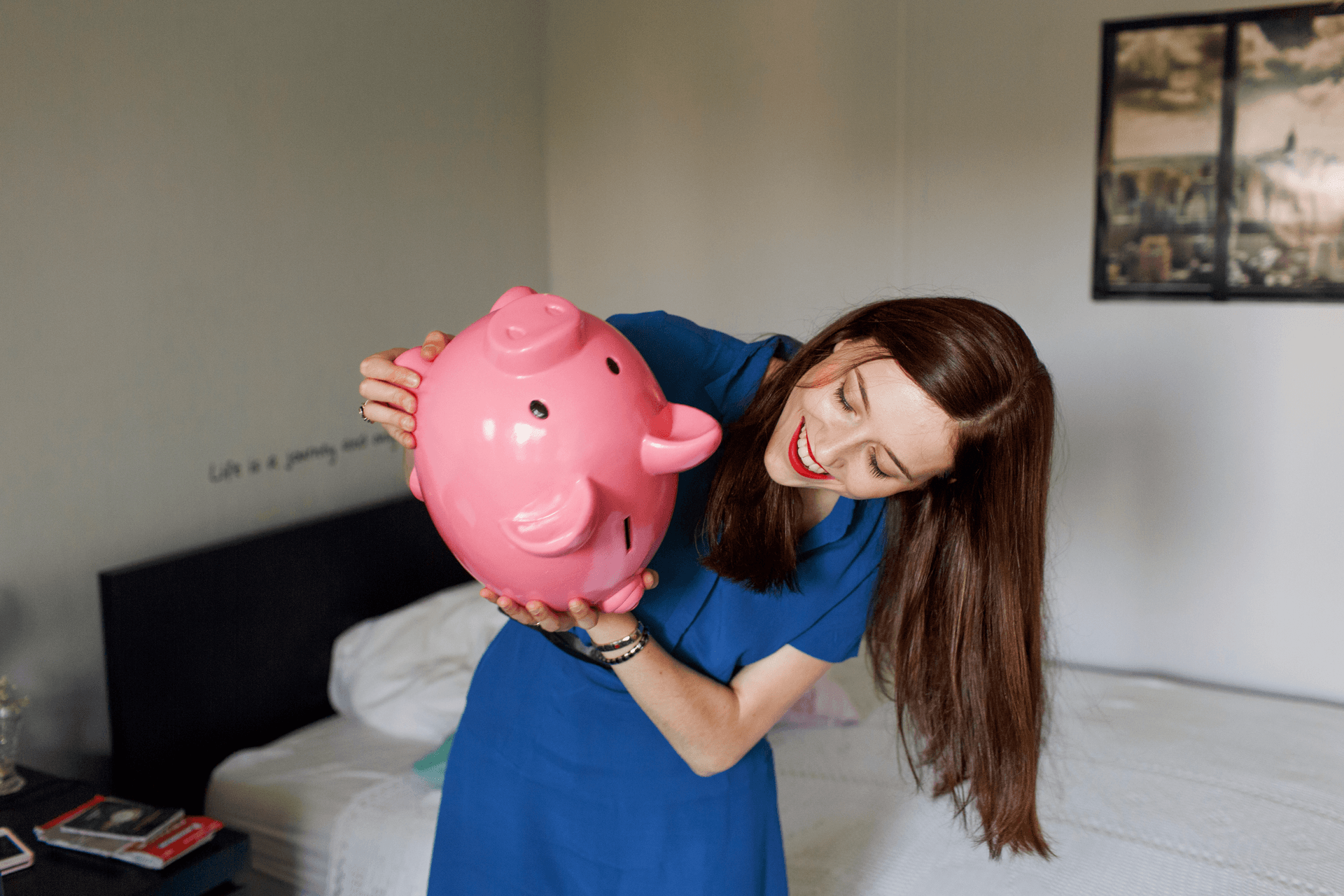 Een vrouw  houdt een spaarvarken ondersteboven vast.