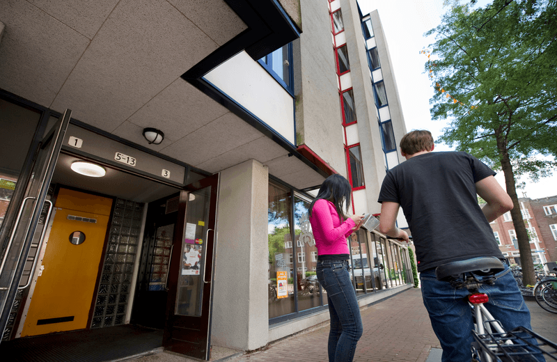Twee studenten staan voor de portiek van hun studentenwoning