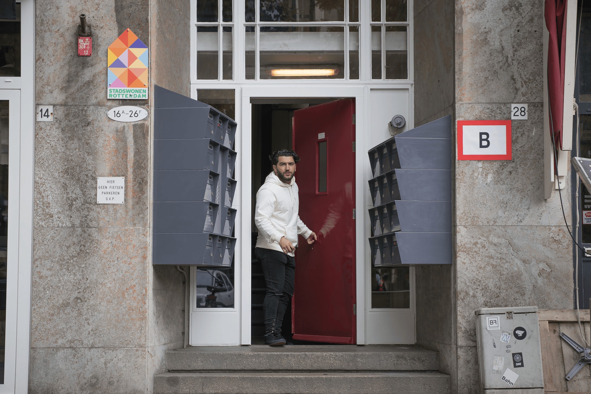 Man loopt vanuit een portiek naar buiten.