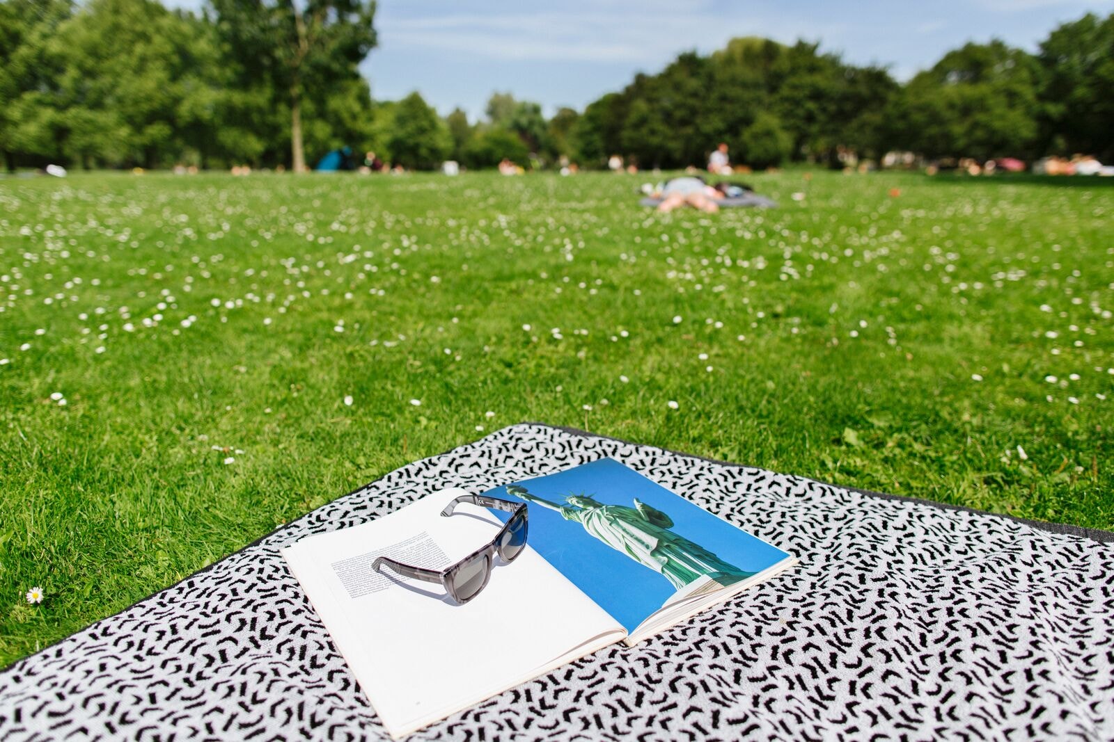 Een kleed in het park, met een zonnebril en tijdschrift erop