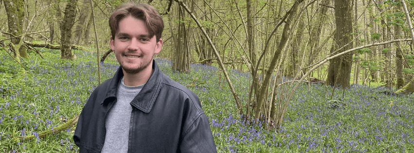 Persoonlijke foto van Tijs waar hij lachend in het bos staat.